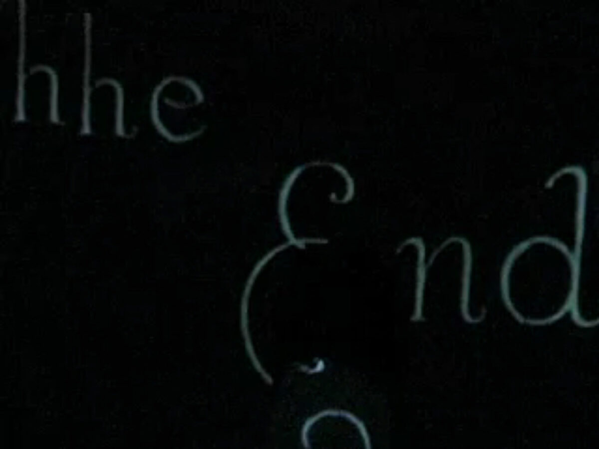 Still image captured from a performance of the 2boys.tv cabaret performance "Casta Diva".  Final projection on the back of the stage, 'the End", white letters in a cursive script on a black background. Projection is a clip from the 1927 silent film "Wings", directed by William Wellman.