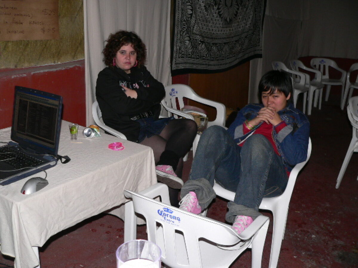 The photo shows Meras efímeras members Artemisa Téllez and Chichis Glam relaxing after a party in 2005. They are seated and look exhausted.