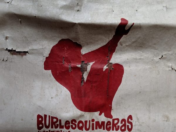 The photo shows a Burlesquimeras promotional apron designed by Emilio Rapp. It is a white vinyl apron featuring the silhouette of a woman, which was one of the Burlesquimeras logos, in red screen printed ink.